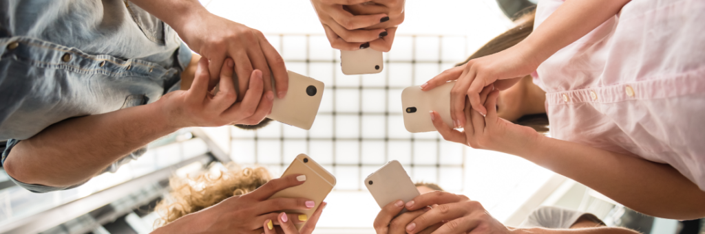 Group of people standing in a circle, seen from below, using their smartphones to create content with Biteable video maker.