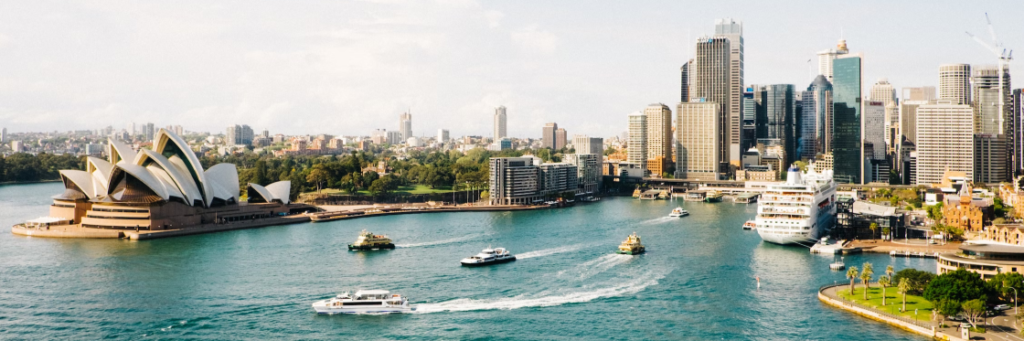 Aerial view of sydney harbour featuring the opera house, city skyline, and boats.