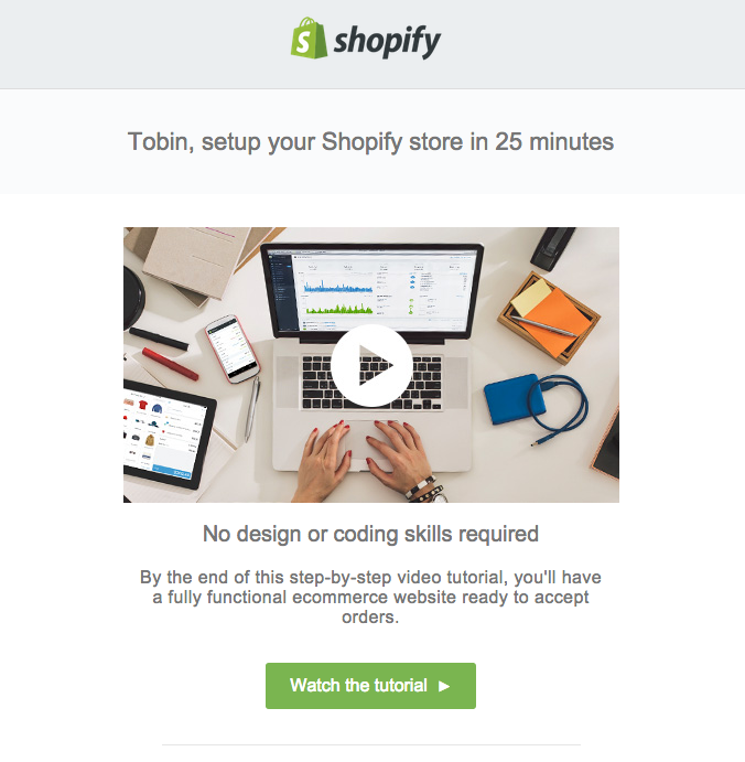 Overhead view of a person working on a laptop with Shopify's promotional message encouraging setup of an online store and highlighting how to embed video in email.