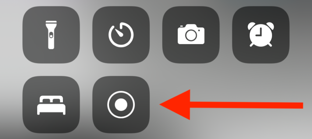 A set of grayscale icons on a dark background with a red arrow pointing to a camera icon.