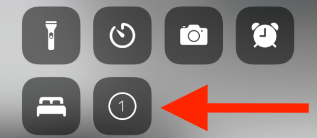 A set of gray app icons on a darker gray background with a red arrow pointing towards a calendar icon with the number 1.
