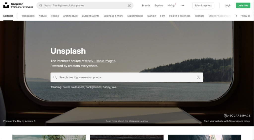 A website homepage for Unsplash, showcasing a search bar and a header describing it as one of the best sites for free images, with a backdrop of a window view looking out to a landscape.