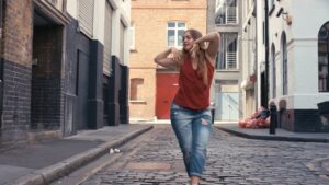 A woman dancing joyfully in an urban alleyway, captured with the Biteable video maker.