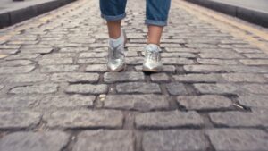 Person walking on a cobblestone street wearing metallic sneakers, captured by Biteable video maker.