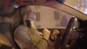 A woman smiling and dancing to music while creating a Biteable video at night.