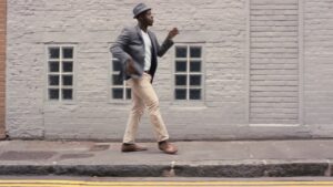 A man in smart casual attire stepping off the curb onto the street, featured in a Biteable video.