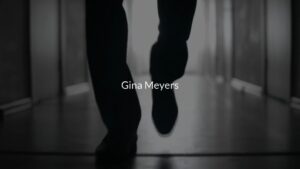 A silhouette of a person's dangling feet, with the name "Gina Meyers" displayed below, created with Biteable video maker.