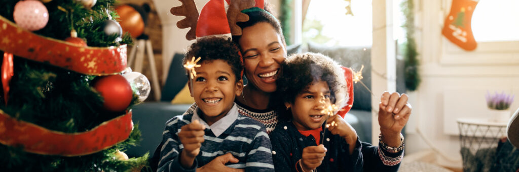 A joyful family with two children holding sparklers, celebrating Christmas at home, surrounded by festive decorations and creating memories for a Biteable video maker.