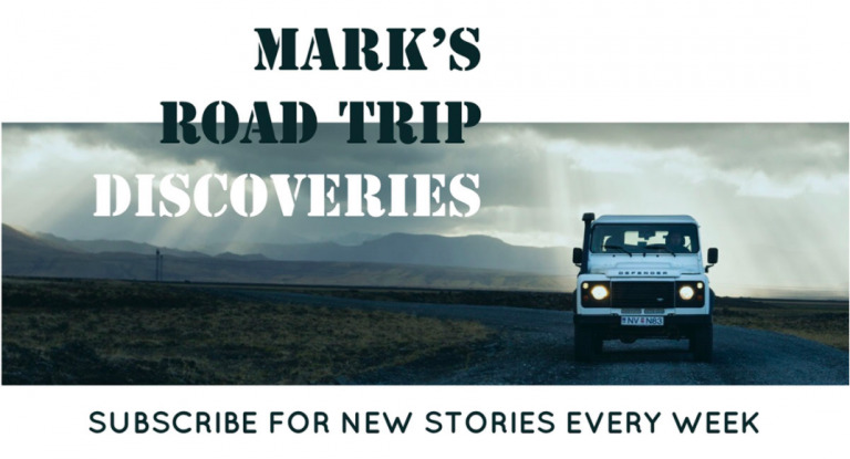 A vehicle drives on a desolate road under stormy skies, with text overlay "mark's road trip discoveries" and a subscription prompt.