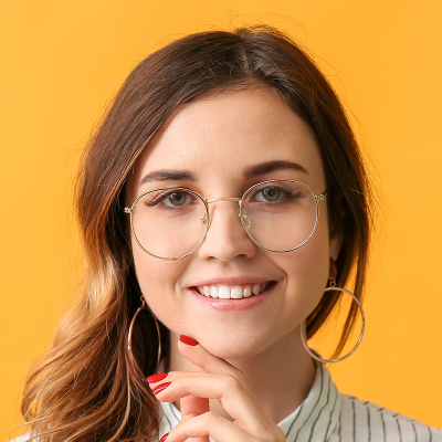 Portrait of a smiling young woman wearing large round glasses and hoop earrings against a yellow background.