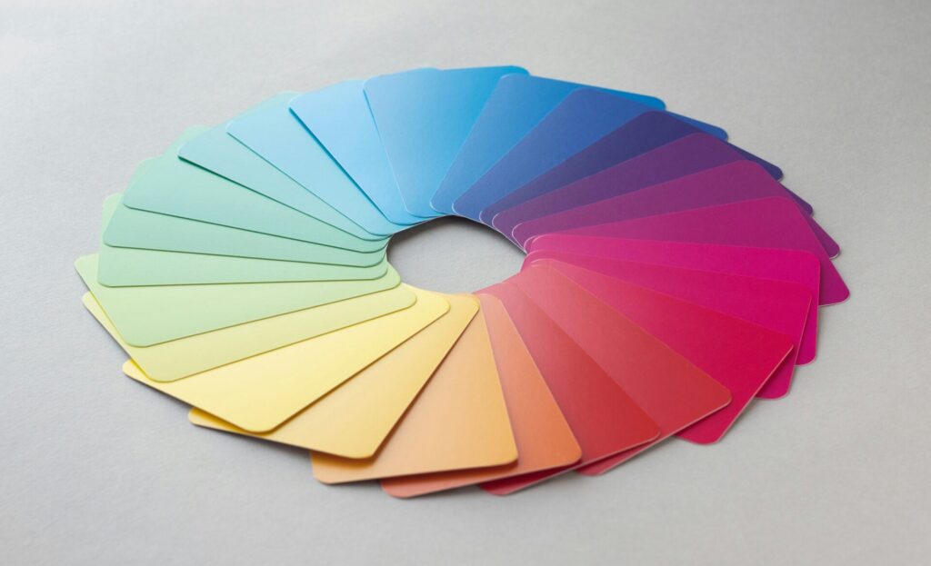 A circular arrangement of color swatches laid out in a gradient from green, yellow, and orange to blue, purple, and pink on a light grey surface serves as stunning color inspiration.