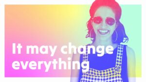A woman wearing sunglasses and a checkered dress smiles in front of a colorful gradient background with the text "It may change everything.