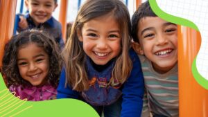 Four young children smiling and leaning close together outdoors on a playground, with orange bars and decorative green shapes framing the image.
