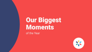 Red background with white text reading "Our Biggest Moments of the Year." A partial blue circle appears on the left and a small multicolored circle is at the bottom right.